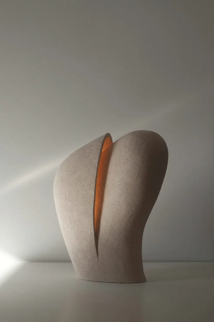 Mātra Table Lamp in Ceramic on white tabletop and gray background, low lighting