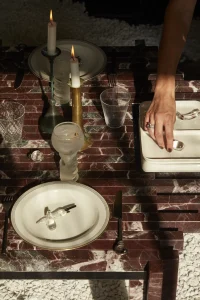 Dining table dressed with handmade ceramic plates, glassware and linen in a warm neutral palette