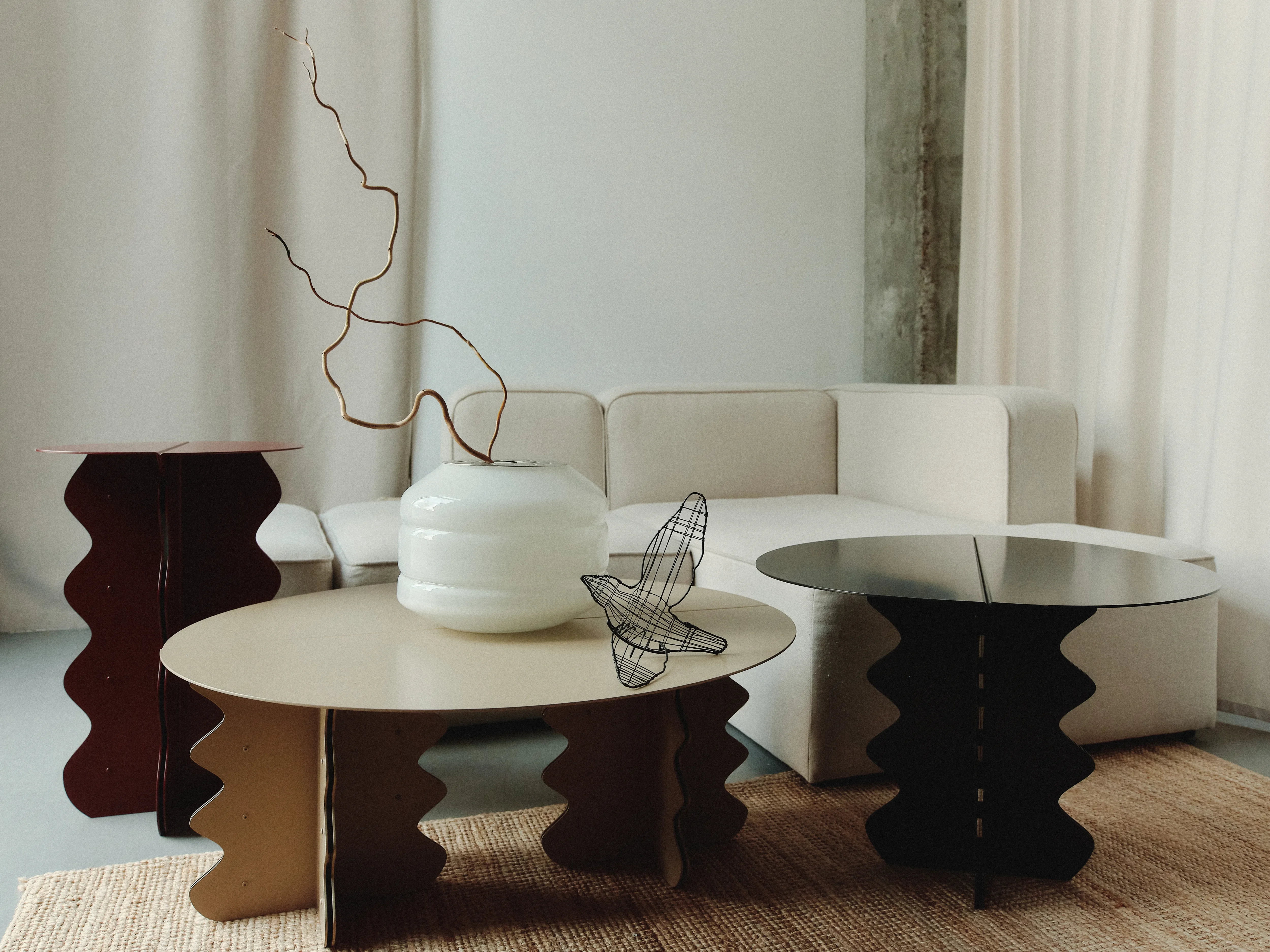 Hvylya cocktail table in powder-coated metal, its wave-shaped base curving under a round top