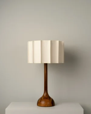 Pata De Elefante Medium Table Lamp in ivory parota wood on a pedestal, front view.