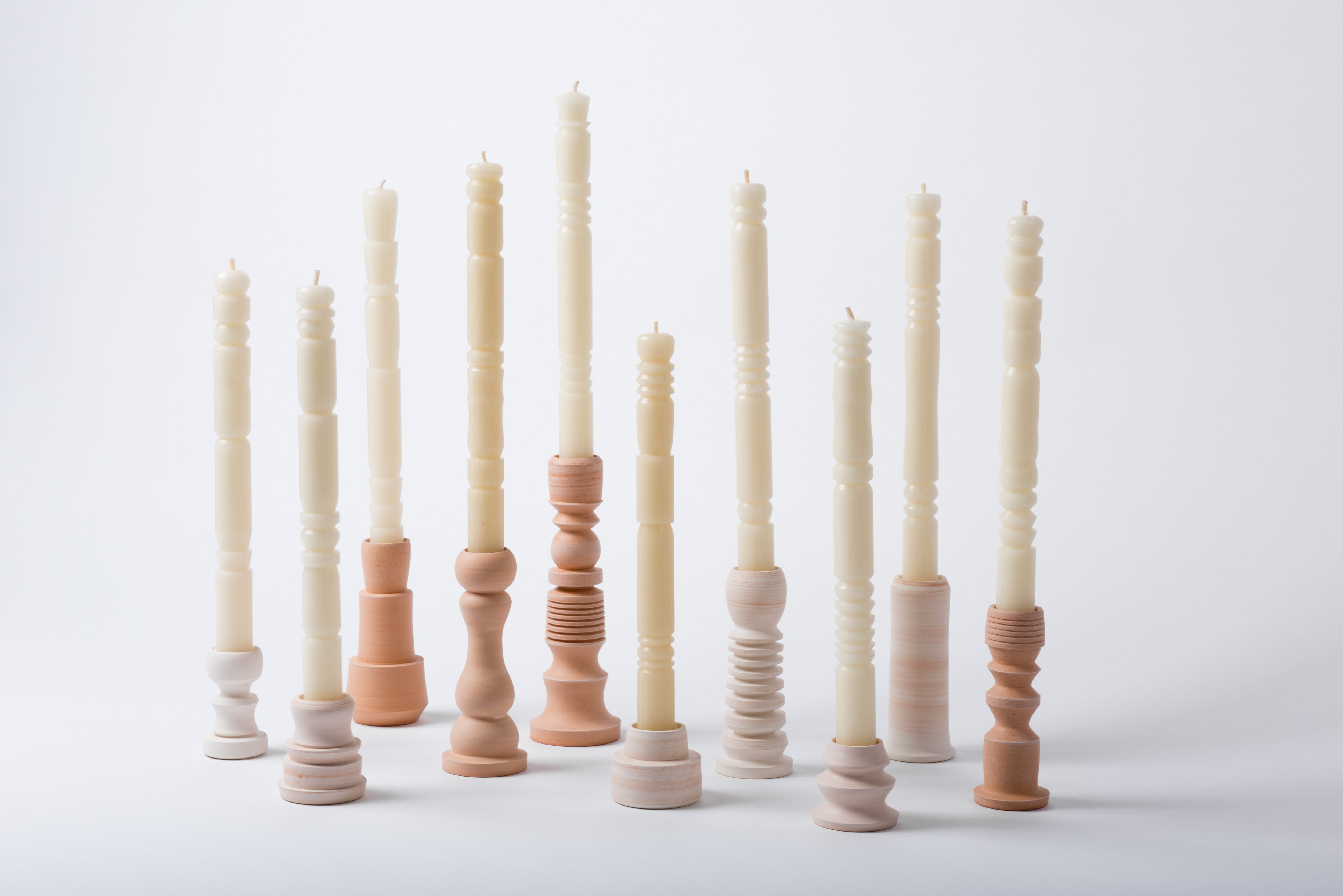 Días en Vela candleholders, turned in pink and terracotta tones holding tall cream taper candles, by Popdots Studio