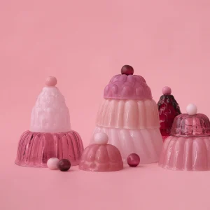 Jello glass cloches in shades of pink, from opaque rose milk to translucent raspberry, shaped like jelly desserts on a pink background, by STUDIO BERG