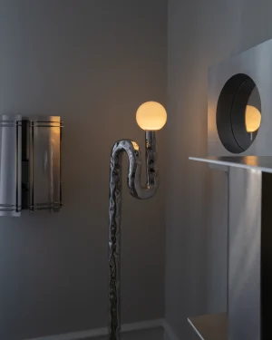 Lasso Floor Lamp in mirror-polished stainless steel on the floor, front view.