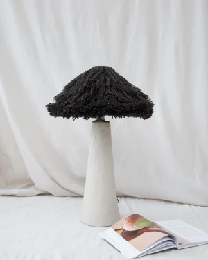Black Wool Table Lamp in light clay biocomposite and black wool on a table, front view.