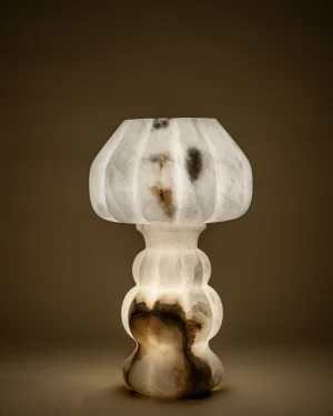 Noura Table Lamp in solid alabaster with veined texture, on a table, front view.