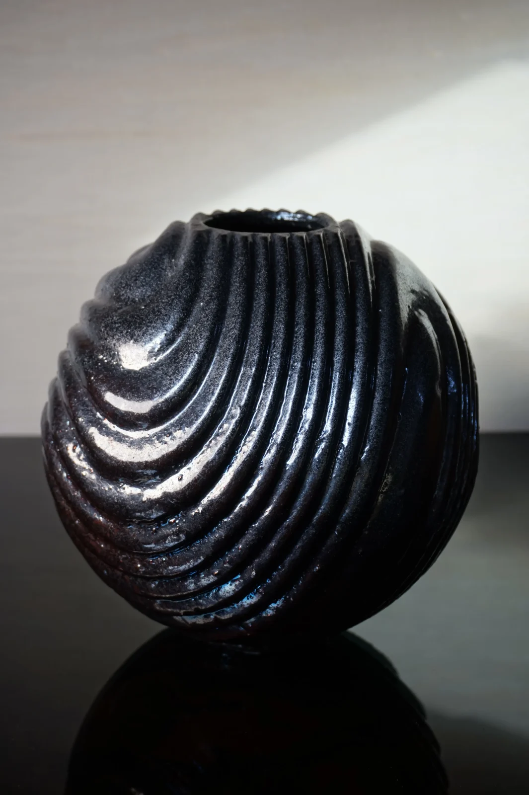 Raku-fired ceramic urn vessel in deep blueberry, its surface flashed by the flame