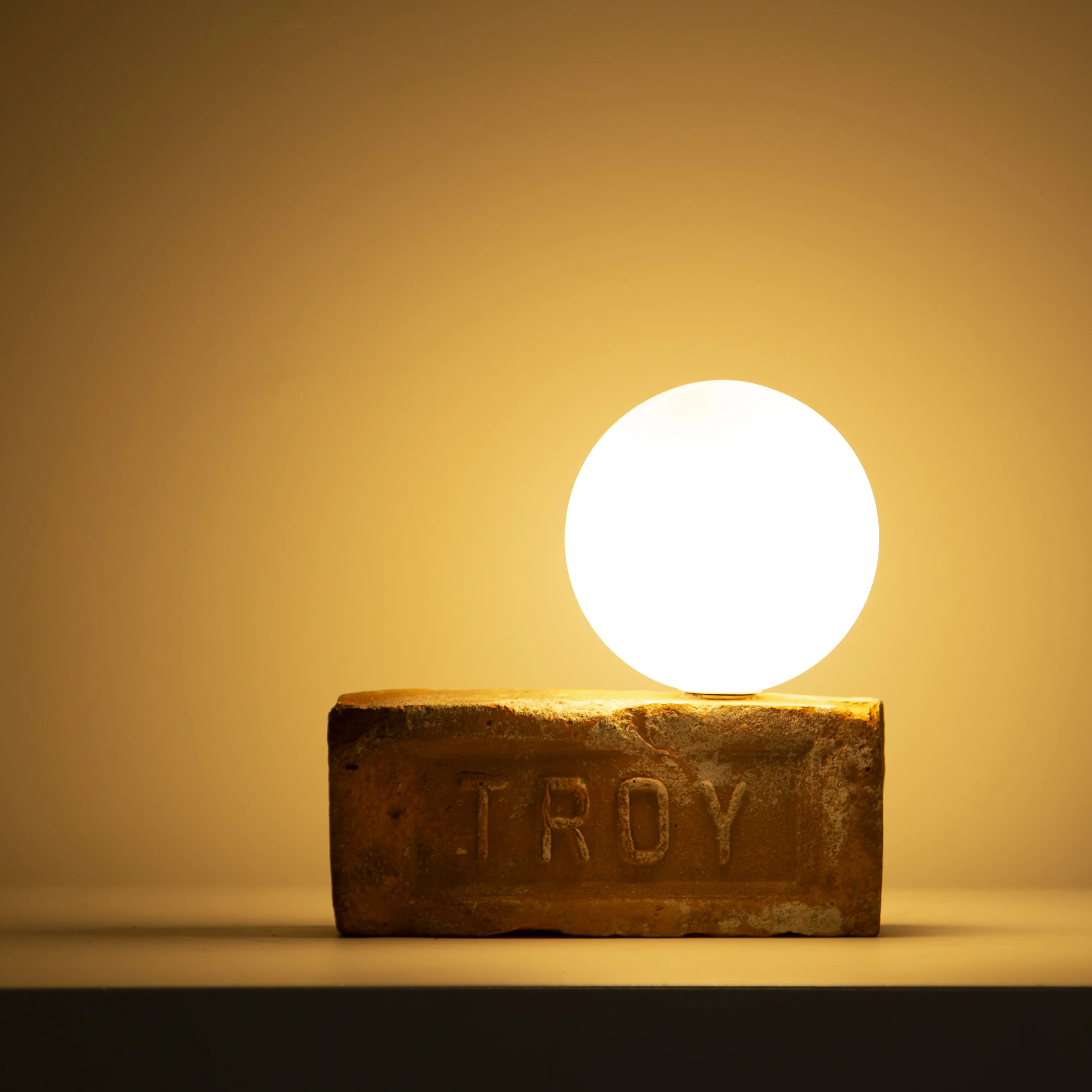 Helen table lamp with reclaimed brick base and frosted glass globe by Solmistudio