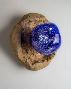 Asea No.13 Wall Sconce in cobalt blue glass and tan stoneware on a wall, angled view.