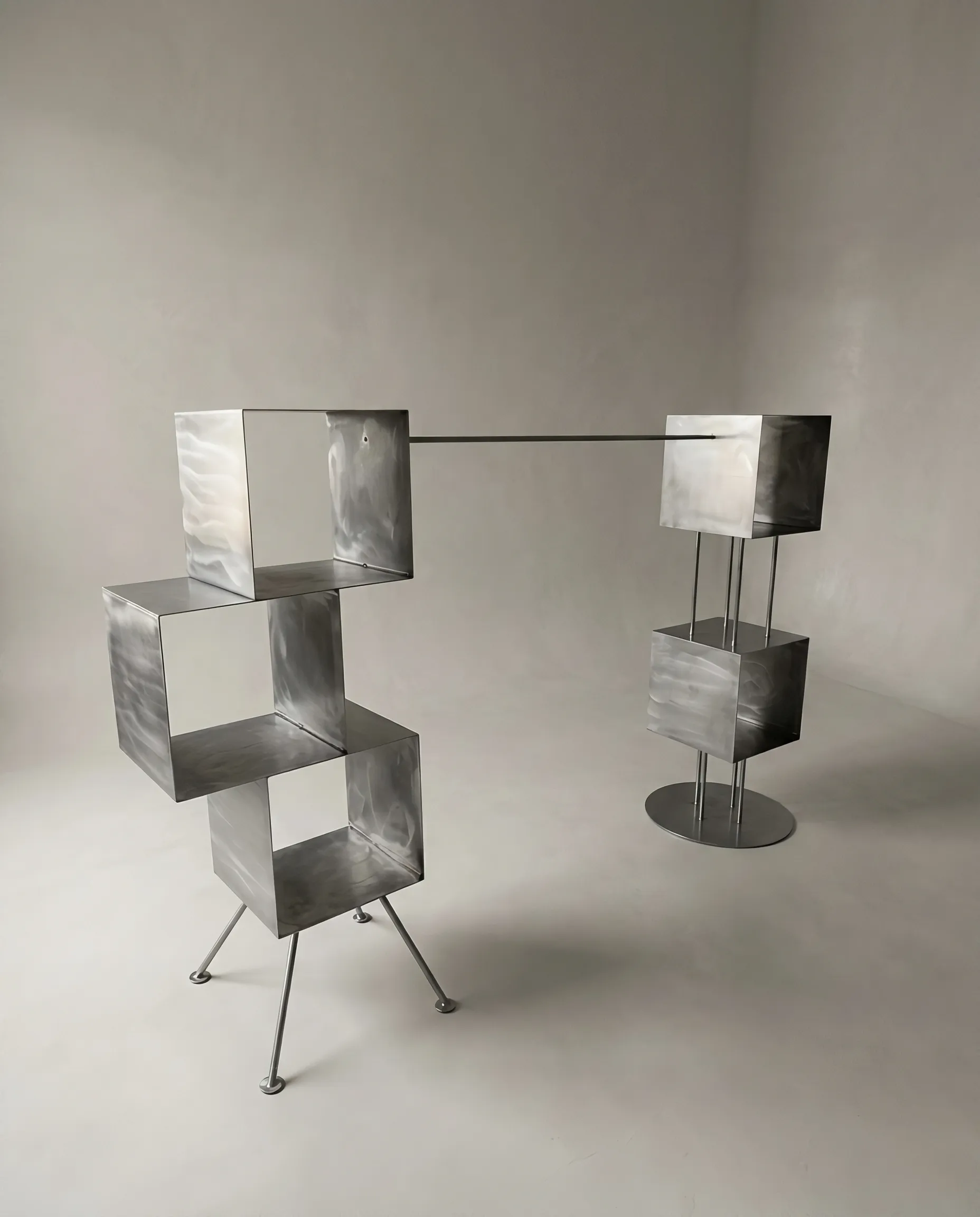 Rubik freestanding shelf of brushed metal cubes stacked at angles on slender legs by Metalmorphosis Studio