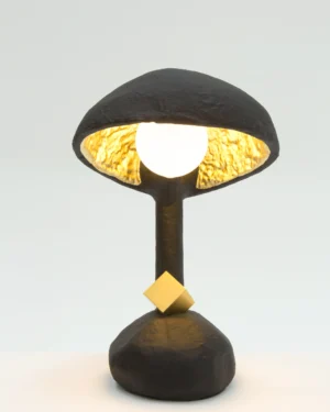 Ic 1 Table Lamp in black resin and foam with a gold-leaf interior, on a table.