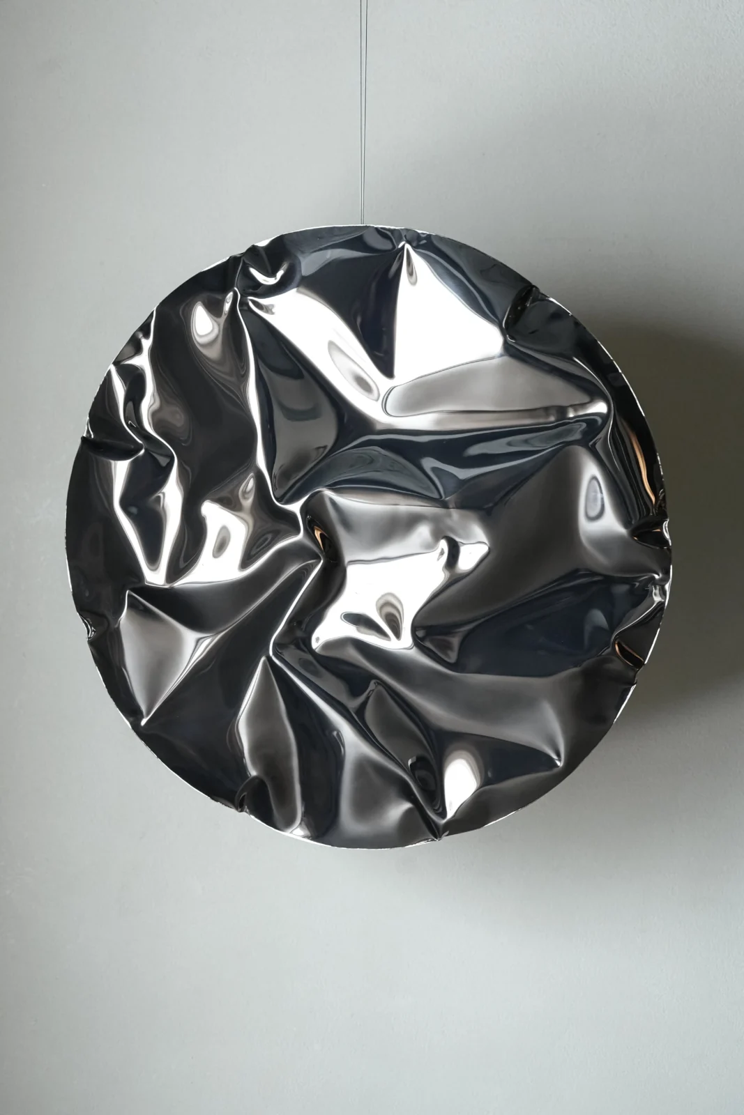 Ramé round wall sculpture in mirror-polished stainless steel with deep folds that reflect the room, by Nitush and Aroosh