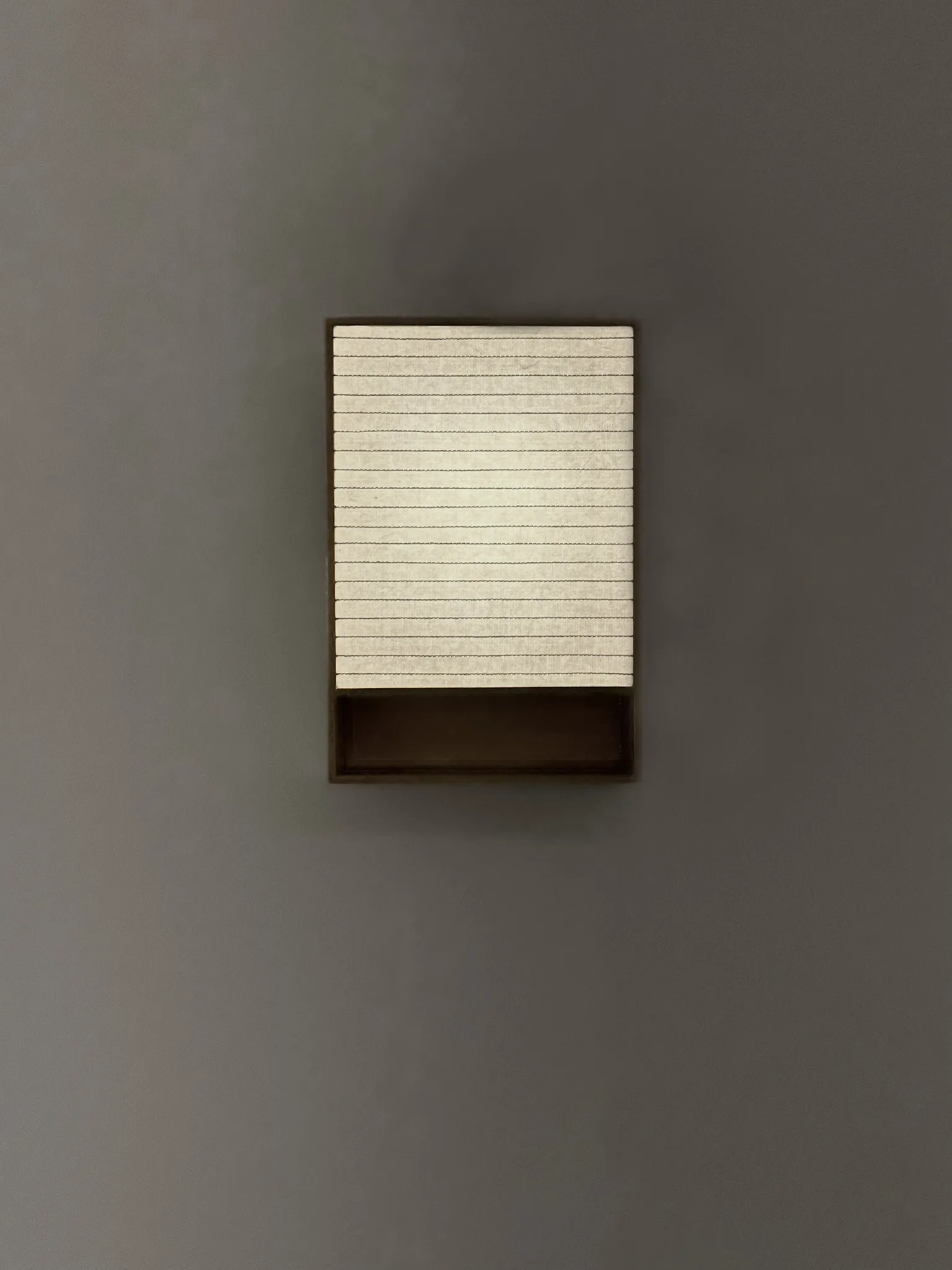 Biiit 010 wall sconce, a brushed brass frame around a lit hanji mulberry paper screen with fine parallel lines, by Bo Ah Kim of MANO design studio