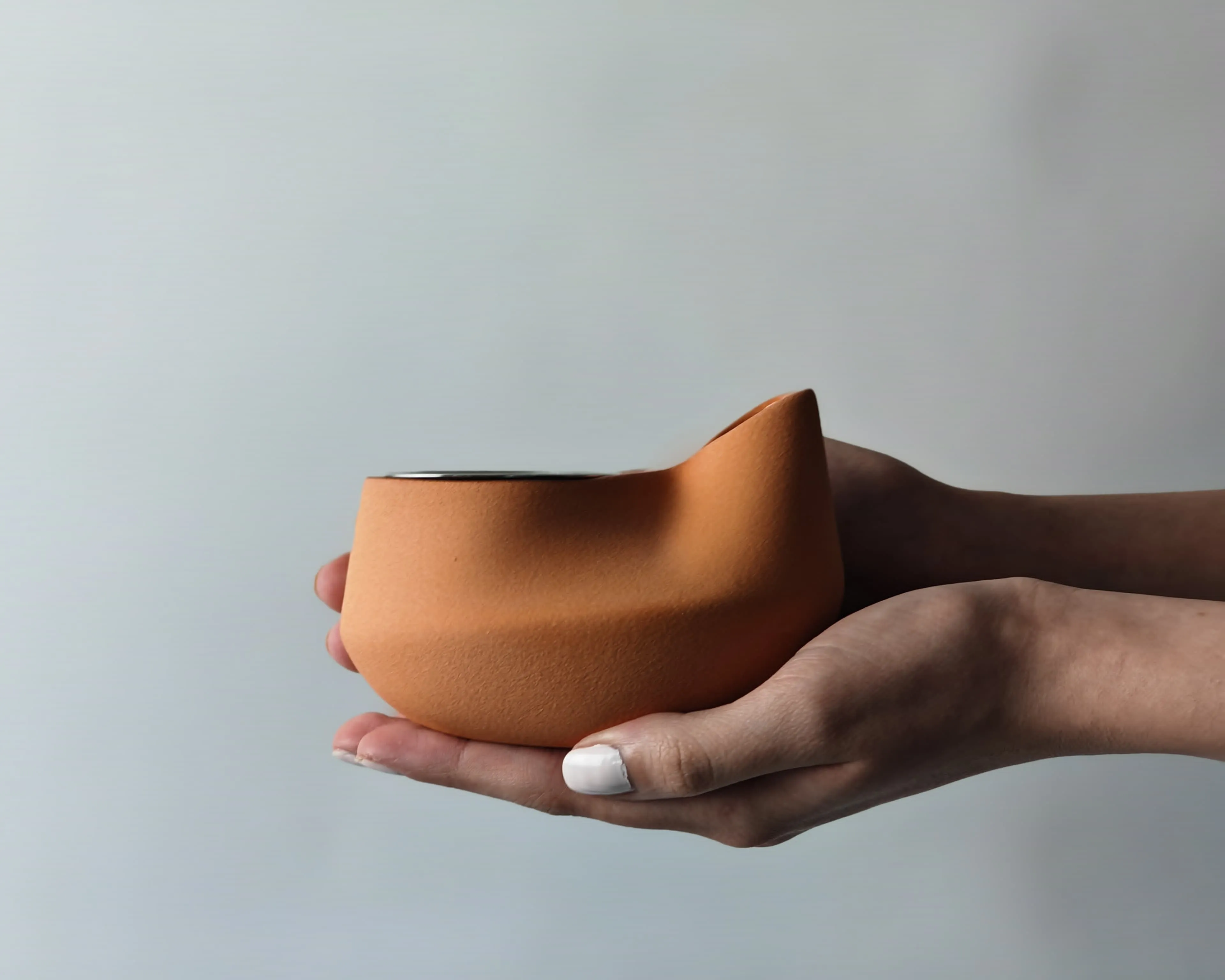 Mini Diya charcoal incense burner in terracotta clay with a pinched lip, held in two open hands, by Twelve Degrees