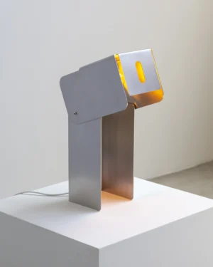 Tauri Table Lamp in brushed stainless steel on a table, front view.