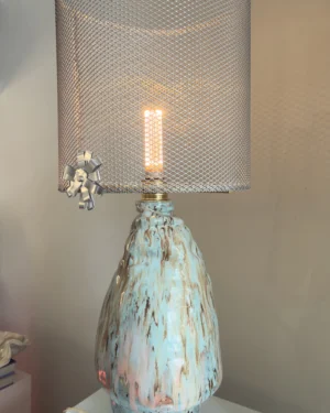 Veil III Tide Table Lamp in stoneware with a perforated aluminum shade, on a table.