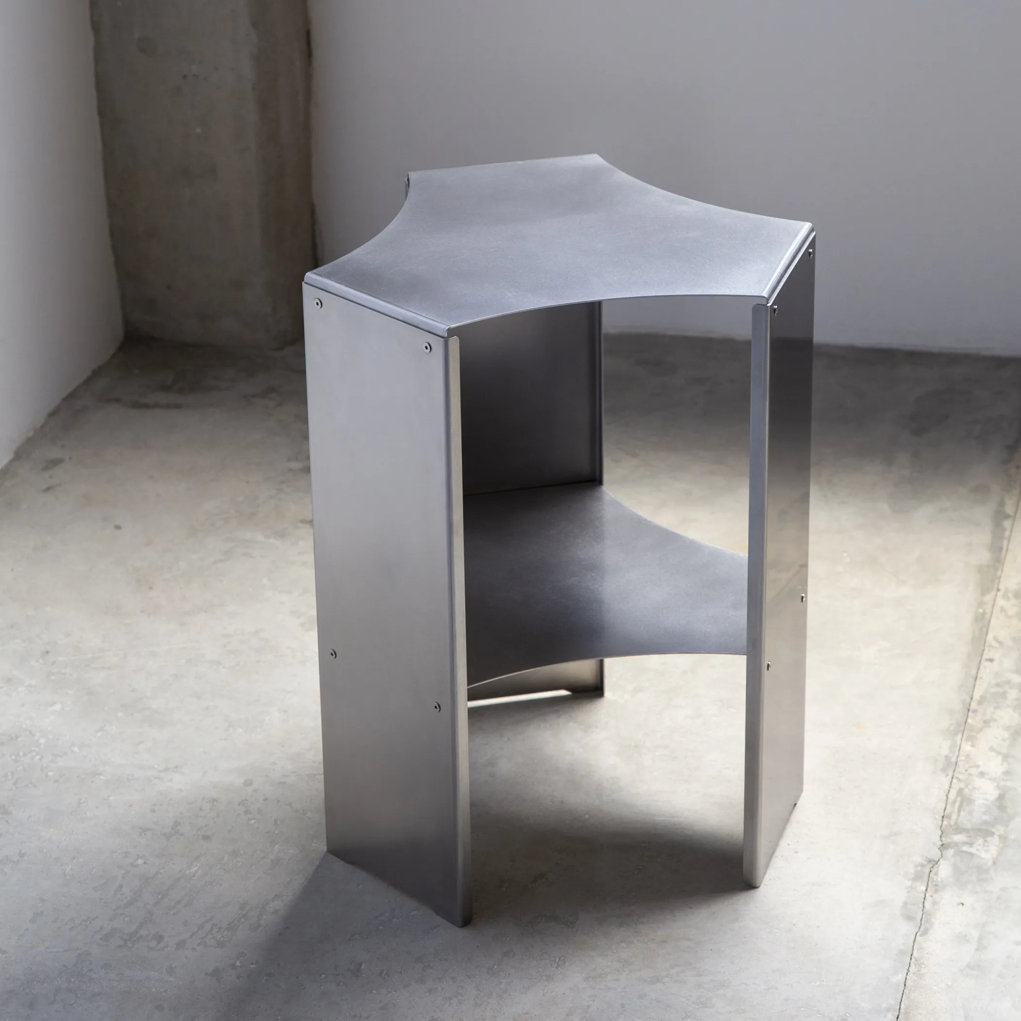 Vortice 50 accent table in folded satin stainless steel with a lower shelf by T44 design studio