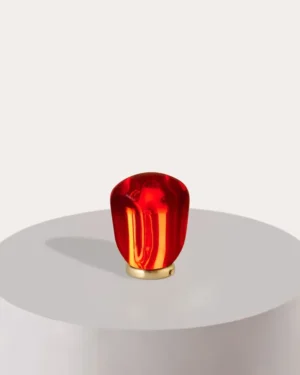Pomy Table Lamp in ruby red resin on a plinth, front view.