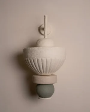 Pebble Wall Sconce in off-white and pale green stoneware on a wall, front view.