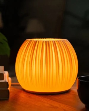 B 1 Table Lamp in ivory biopolymer on a wooden table, front view.