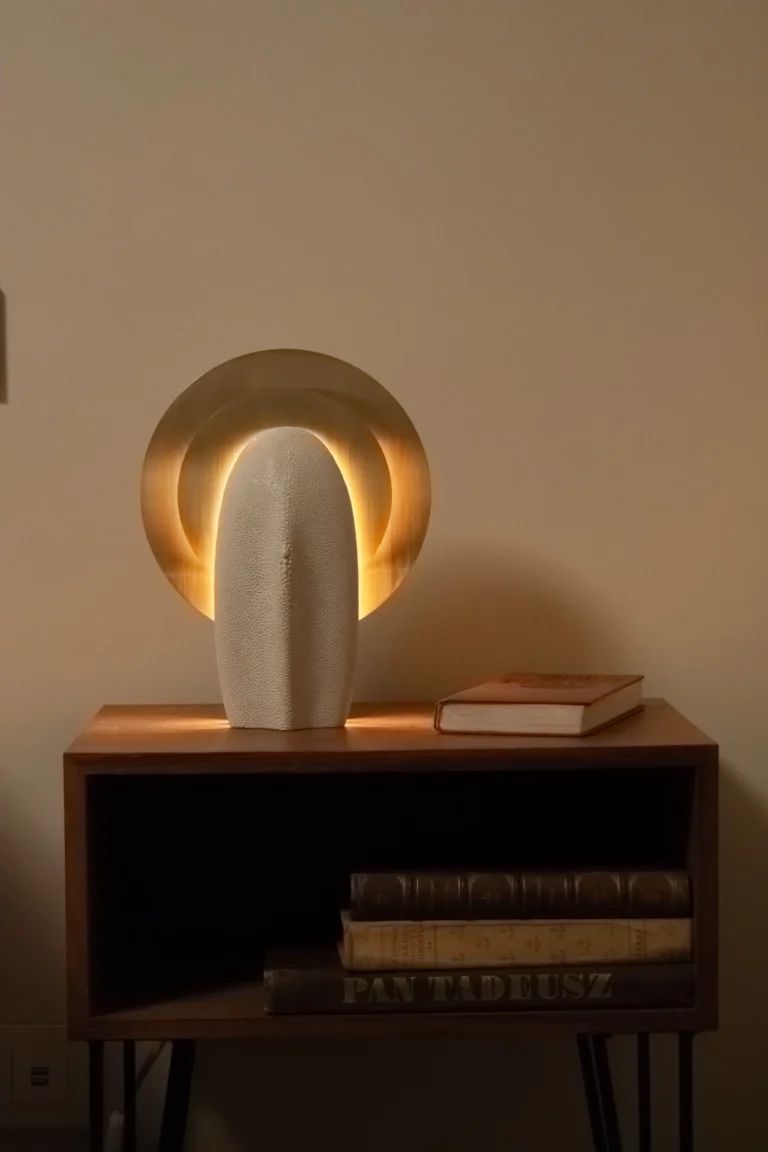 Mother of the Light Table Lamp by PALUCKI Studio in a living space, lit on a wooden shelf unit beside a stack of books