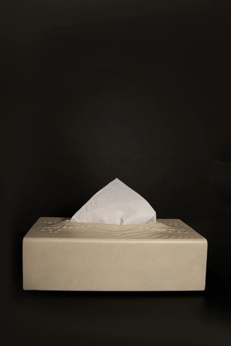 In Case Of Tears by PALUCKI Studio seen from the side, a parchment tissue box with a tissue, against a black background