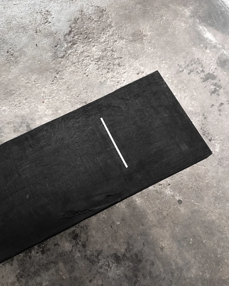 Blackwood Aluminium Bench by case studios seen from above, showing the blackened oak seat and a single inlaid aluminum strip
