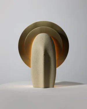 Mother of the Light Table Lamp in ivory galuchat with brass discs on a white surface, front view.