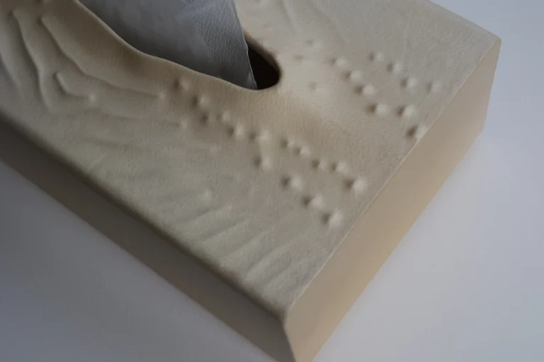 Close-up of the In Case Of Tears tissue box's carved relief of raised dots and ridges on the parchment surface