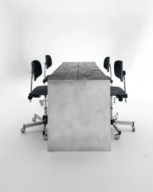 Yakisugi Desk by case studios seen from the end, aluminum panel and charred oak top, with four black swivel chairs