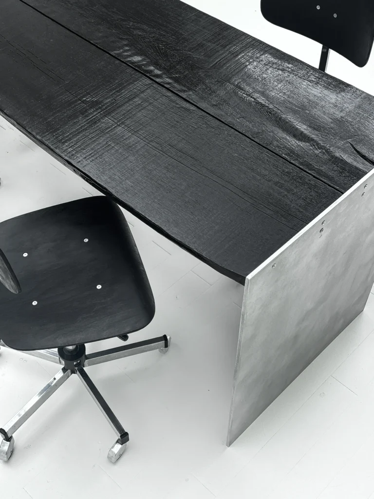 Yakisugi Desk by case studios seen from above, charred oak top with sawn grain beside an aluminum side panel and a chair