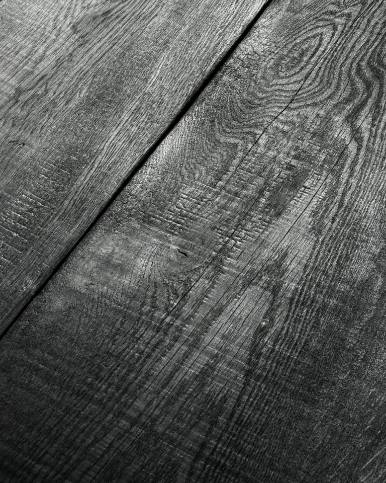 Close-up of the Yakisugi Desk's charred oak top, showing deep grain, a knot and the seam between two boards