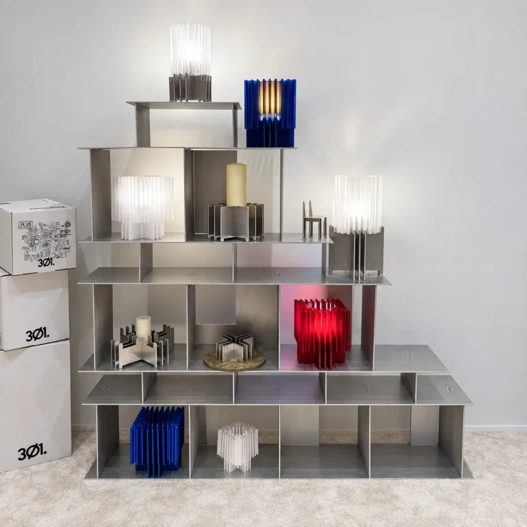 Open Grid Shelves by 301 Design Studio in a showroom, holding lit lamps and colourful pleated objects