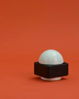 Knstrkt Set Of 2 by Studio Berg, black square base with white crackle-glazed dome lid, on a terracotta background