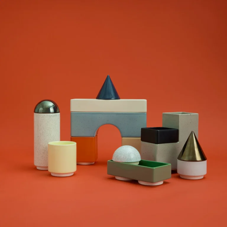 Knstrkt Set Of 14 by Studio Berg, arch block, green tray, yellow cup and cones, on a plain orange background