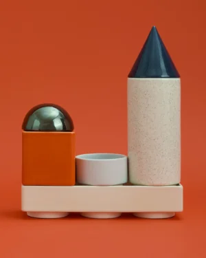 Knstrkt Set Of 6 by Studio Berg, stacked orange, white speckled and blue glazed ceramic pieces on a plain orange background