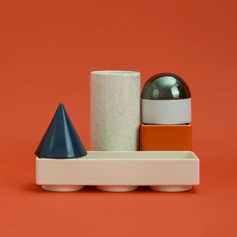 Knstrkt Set Of 6 by Studio Berg seen from the front, a blue cone and speckled cylinder resting on the long cream tray