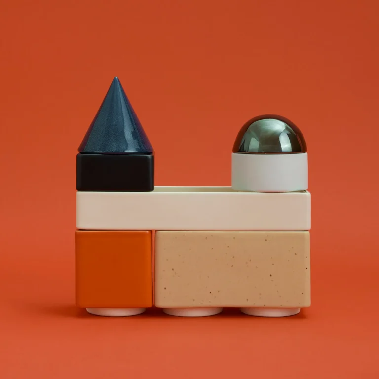 Knstrkt Set Of 7 by STUDIO BERG, stacked glazed blocks with a blue cone and silver dome, on a plain background