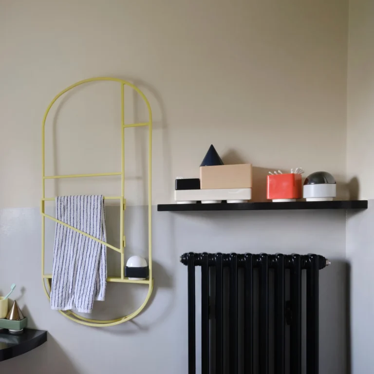 Knstrkt Set Of 7 by STUDIO BERG on a black wall shelf above a radiator, beside a yellow towel rail in a bathroom