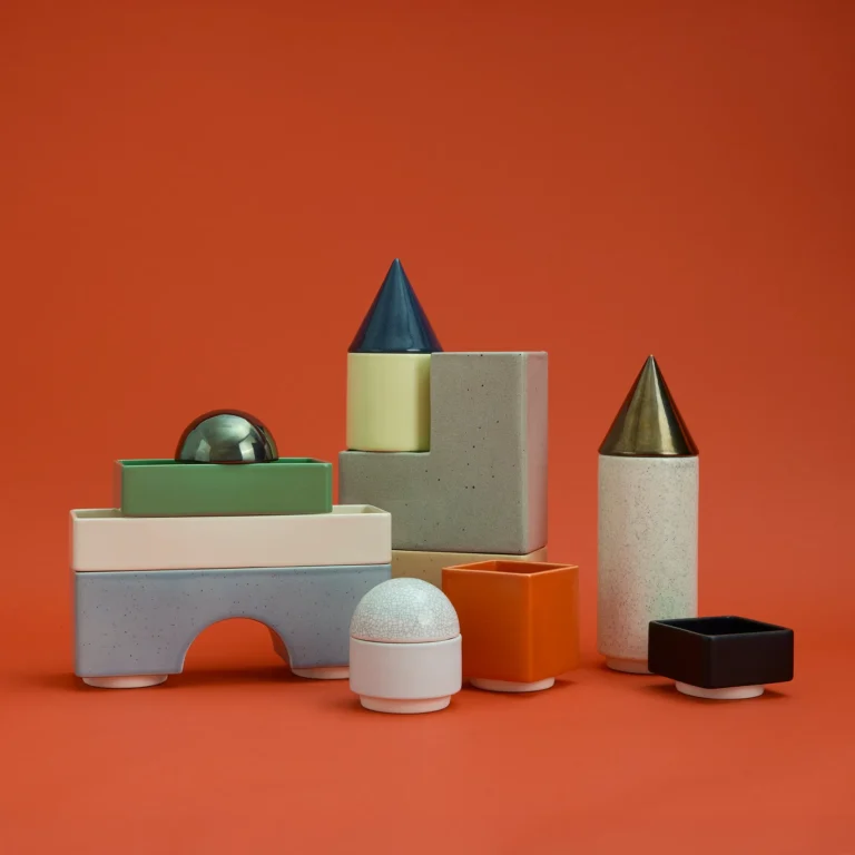Knstrkt Set Of 14 by Studio Berg, stackable glazed ceramic blocks, cones and domes, on a plain orange background