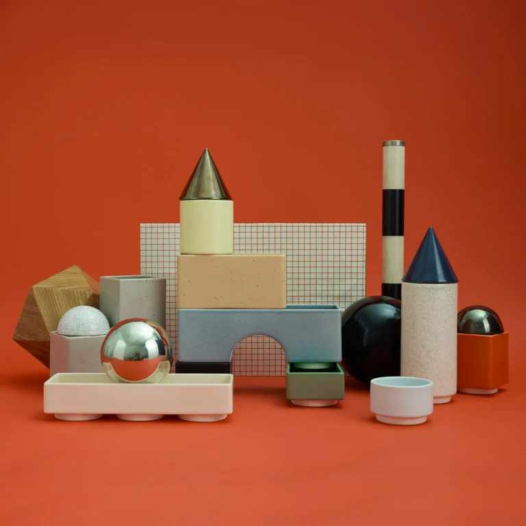Knstrkt Set Of 14 by Studio Berg with a mirrored sphere, wooden shape and grid panel, on an orange background