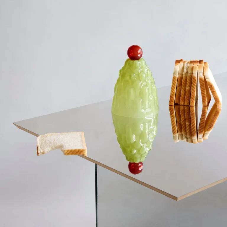 Jello High by Studio Berg, pale green glass cloche with red knob on a mirrored table, beside slices of bread