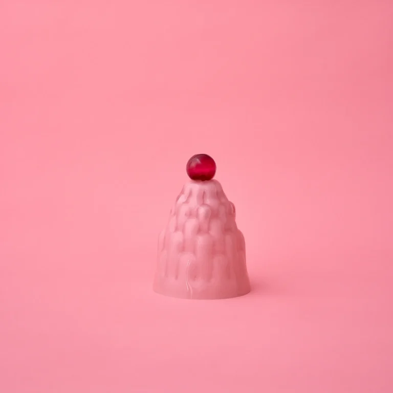 Jello High by Studio Berg, soft pink glass cloche with a dark red knob and ridged surface, on a pink background
