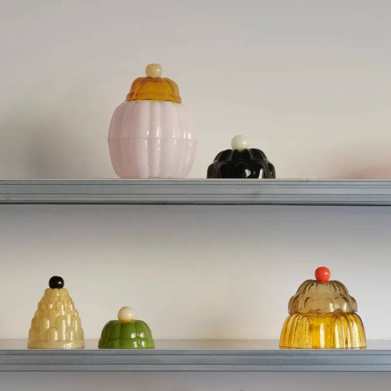 Jello High by Studio Berg on gray shelves, glass cloches in pink, black, cream, green and amber with round knobs
