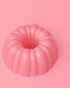 Jello L Hand-blown Glass Cloche by STUDIO BERG seen from above, fluted pink glass ring shape on a pink background