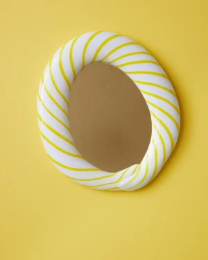 Yellow Candy Mirror by Studio Berg, oval wall mirror in a twisted white glass frame with yellow stripes, on a yellow wall