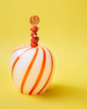 Red Candy Side Table by STUDIO BERG, white glass with orange spiral stripes, topped with a lollipop and sweets