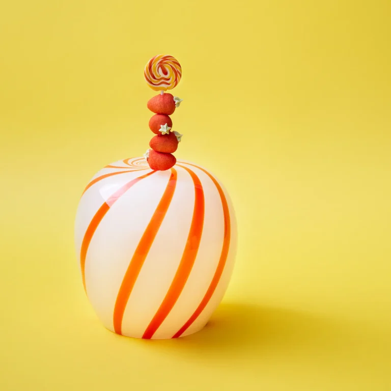 Red Candy Side Table by STUDIO BERG, white glass with orange spiral stripes, topped with a lollipop and sweets