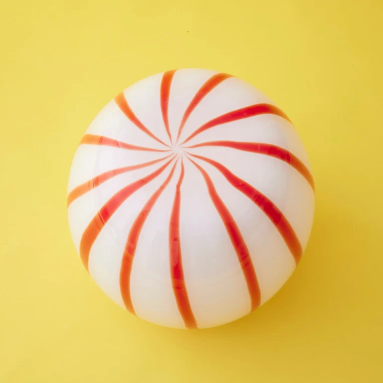 Red Candy Side Table by STUDIO BERG seen from above, red and orange stripes spiralling out from the centre of the glass top