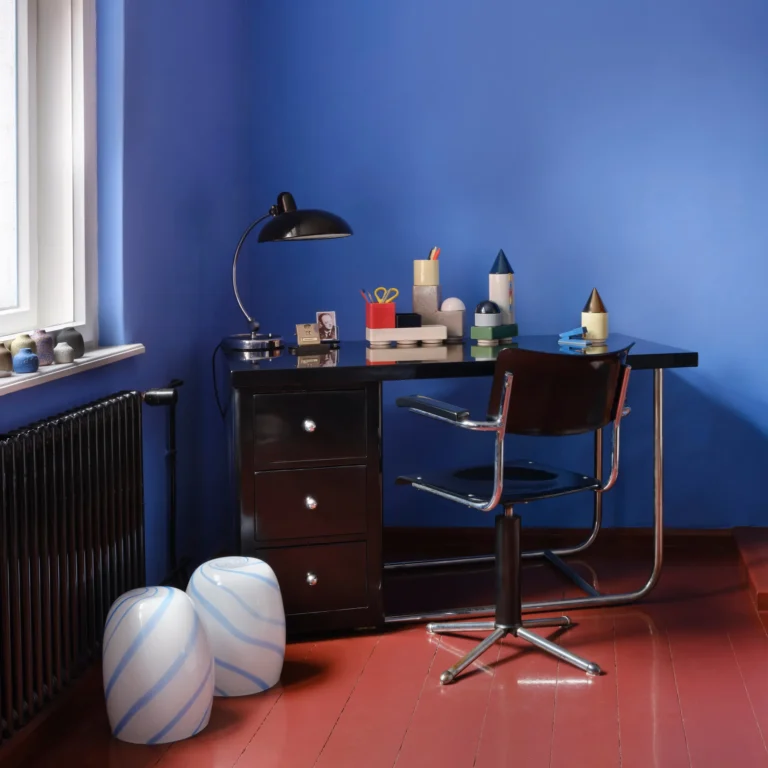 Blue Candy Side Table by STUDIO BERG in a study, two striped glass stools by a black desk and a blue wall