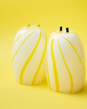 Yellow Candy Side Table by Studio Berg, two white glass stools with swirling yellow stripes, one with yellow knobs
